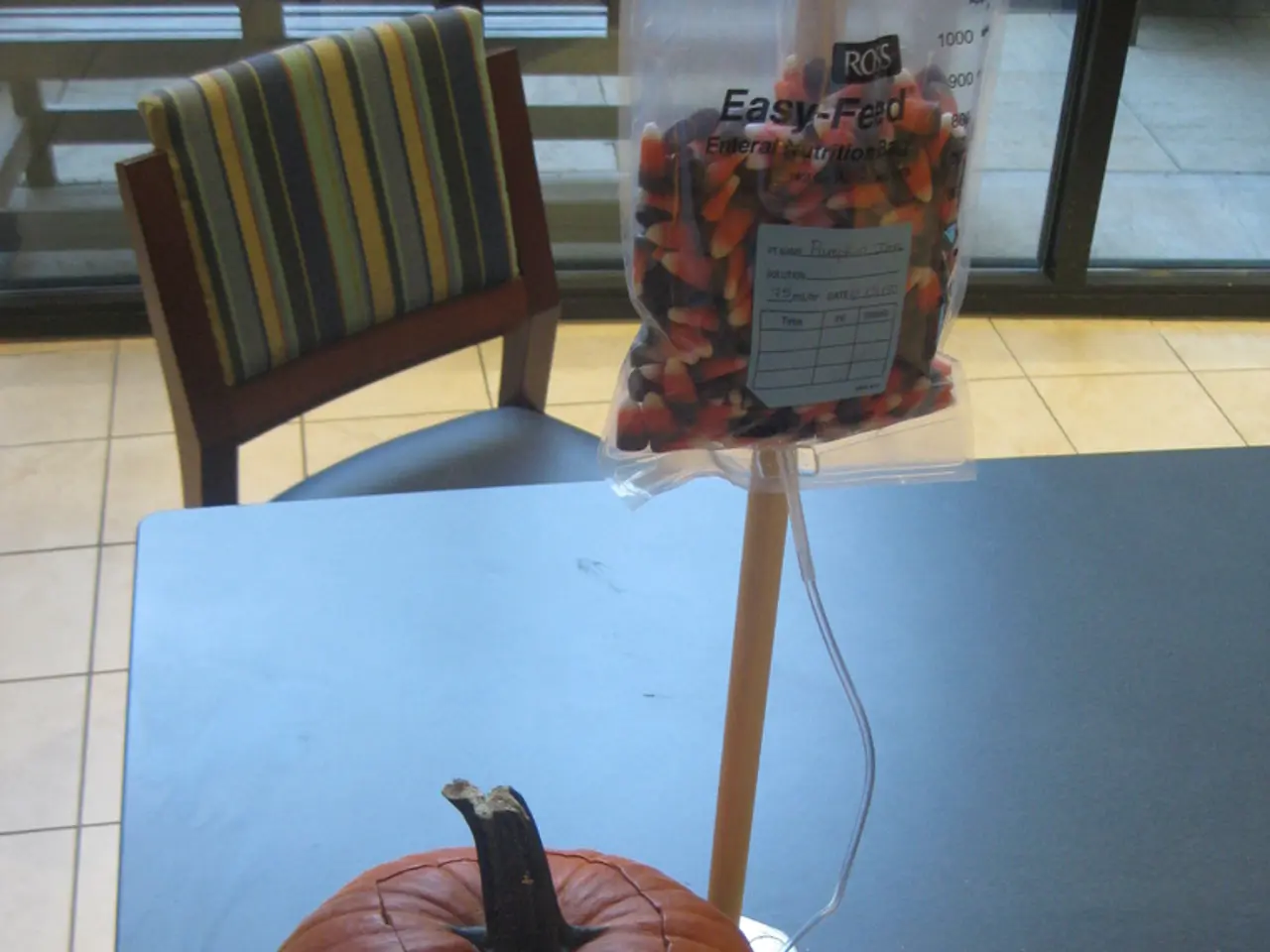 In this image there is a table on which there is a pumpkin. There is a stick and a packet beside...