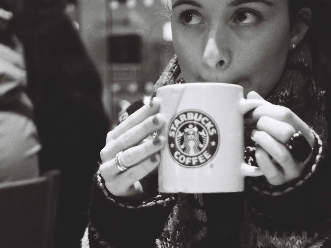 In this image there is a person wearing black color dress drinking coffee.