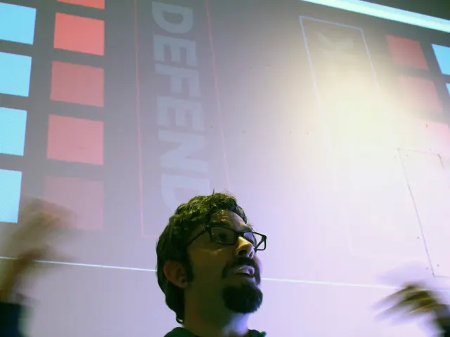 In this picture I can see a person wearing spectacles, behind we can a board on which we can see...