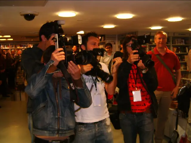 People are standing in a room wearing id cards and holding cameras. There are books in the book...