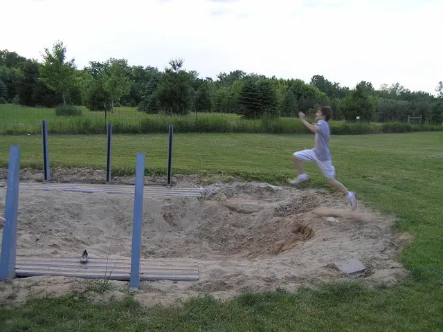 In this image there is a person performing the action of running and jumping onto a sand, behind...