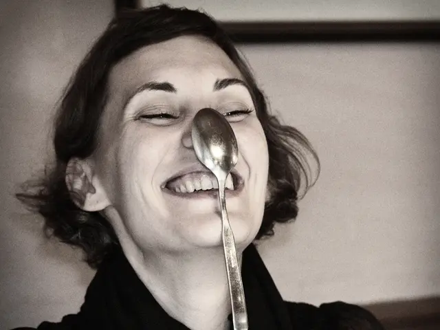 In the picture we can see a woman keeping a spoon on her nose and coughing and she is in black...