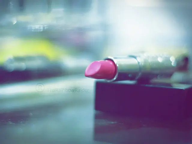 In this image I can see the lipstick which is in pink and silver color. It is on the black color...