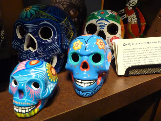 In this image I can see skulls on the table which are painted in different colors, beside that...