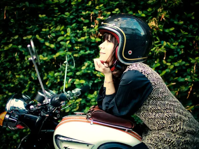 The women is sitting on a bike and there are trees beside her.